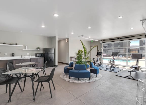 Spacious clubhouse with overhead doors and a pool view. A workout area to the right, and a kitchen and seating on the left. at Altitude, East Wenatchee, Washington