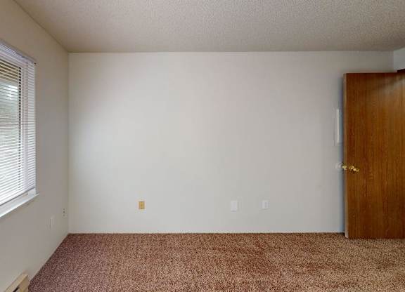 Second bedroom in a 2-bedroom unit at Heritage Grove Apartments Renton WA, with soft carpeting, large closet space, and a light-filled window.