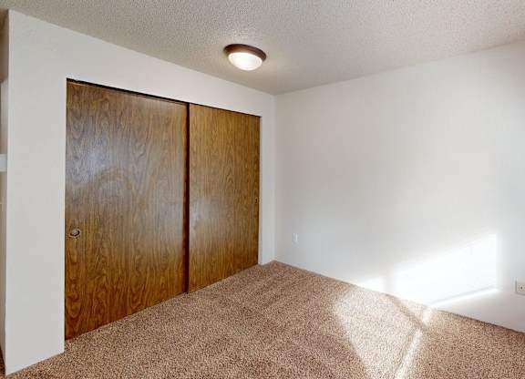 Comfortable bedroom at Heritage Grove Apartments in Renton WA with neutral walls, carpeted floor, and a window view to the outdoors.