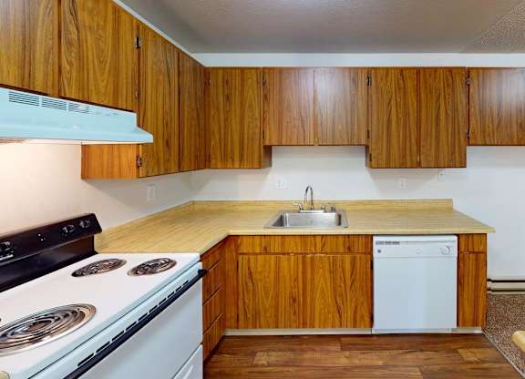 Well-equipped kitchen at Heritage Grove Apartments in Renton WA, with wood-grain cabinetry, full-size refrigerator, and modern finishes.