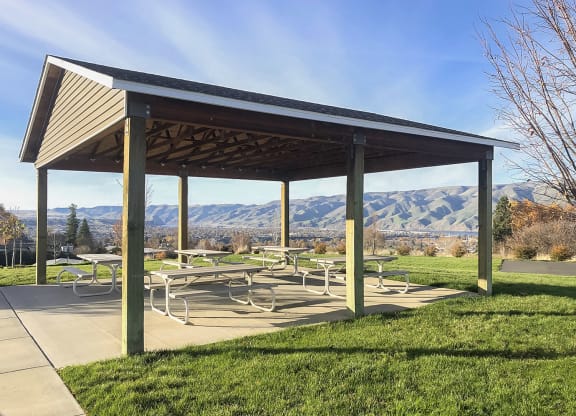 Outdoor community pavilion with many benches surrounded by grass and overlooking the Snake River mountain range.at Canyon View, Lewiston Idaho.