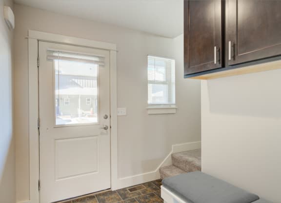 an entryway with a white door with a window and a staircase with a bench at Copper Pines, Montana