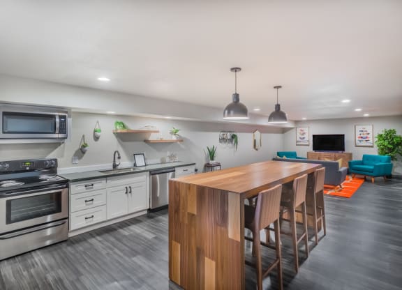 Clubhouse kitchen with large island, oven, stove, microwave, sink, and plants.at Cedarwood, Washington, 98801