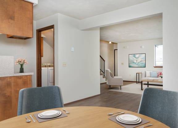Open-concept dining area with wood-style flooring, table, and 2 chairs. Looking into the large living room to the right. at Hawks Prairie, Olympia, 98516