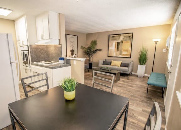Dining area flows into kitchen and living room. Staged with dining set, couch, table, and plants