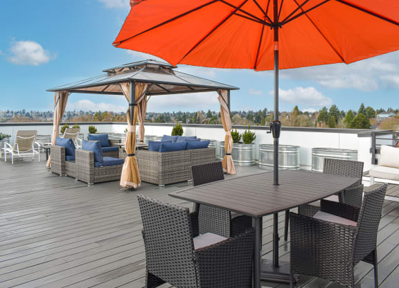 a rooftop patio with tables and chairs and an orange umbrella