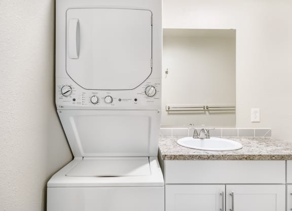 In-home washer and dryer in a bathroom next to the vanity sink with under cabinet storage.at Wildflower, Kennewick, WA 99336