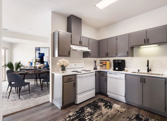 L-shaped kitchen with white appliances, gray cabinets and the dining room behind.at Shoreline Village, Richland