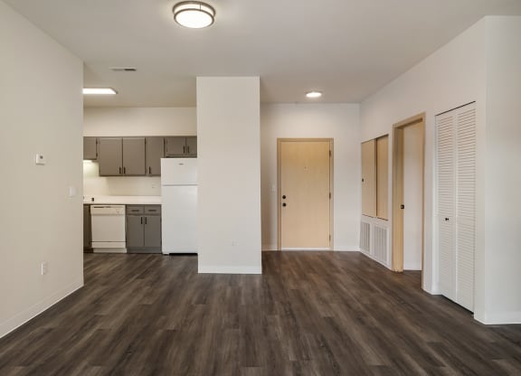 a living room with wood-style flooring, white walls and a kitchen in the background.at Shoreline Village, Washington, 99352