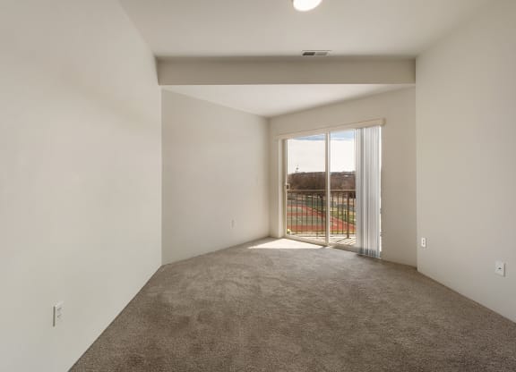 A living room with white walls, taupe carpets, and sunny sliding glass doors to balcony.at Shoreline Village, Richland, WA 99352