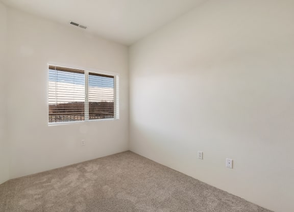 a bedroom with gray carpets, white walls and a sunny window with white blinds.at Shoreline Village, Richland