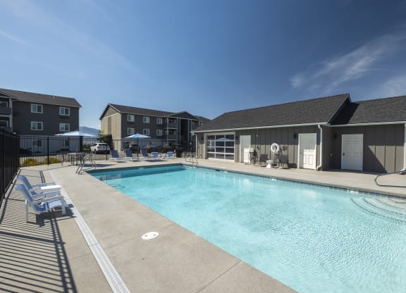 a swimming pool with lounge chairs and umbrellas in front of a building  at Altitude, East Wenatchee