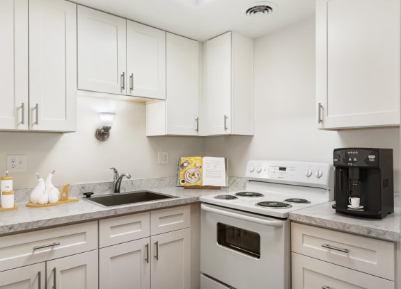 a kitchen with white cabinets and white appliances at Park View Apartments, Wenatchee