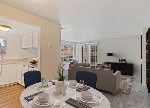 Dining area with view of kitchen leads into carpeted living room, with large window and sliding glass doors.at Capitol Crossing, Olympia, WA