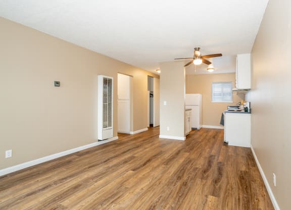 an empty living room with a ceiling fan and a kitchen at Ella 1711 Apartments, Woodland, CA 95695