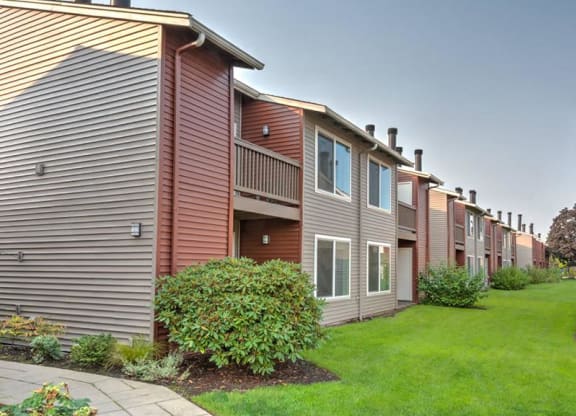 Outside of apartments with patios and balconies. Lined with manicured green lawn and landscaping. at Pointe East, Fife, Washington