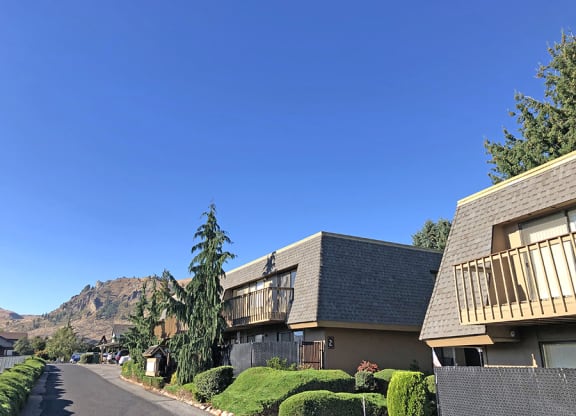 Apartment building exterior with trees, hedges, and a view of the Beartooth Mountains.at Castlerock, Wenatchee, WA
