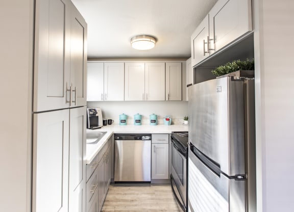 Kitchen in community lounge with stainless steel appliances and new white cabinets at The Lakes Apartments, Moses Lake, WA.