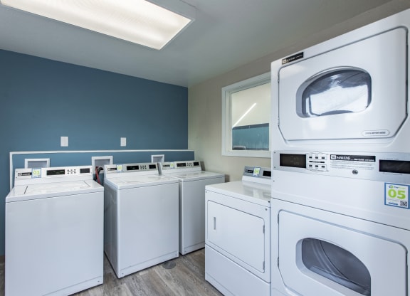 Laundry room showing new white washers and dryers and blue walls at The Lakes Apartments, Moses Lake, WA.