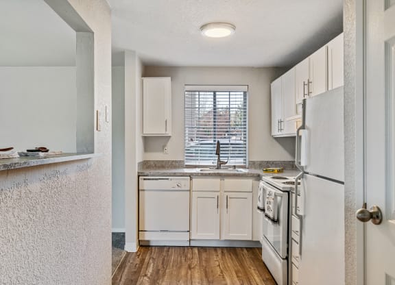 an open kitchen with white appliances and white cabinets