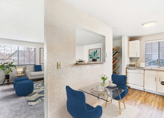 Living room and wood-floor kitchen divided by a textured wall with a looking window and staged with a breakfast table and chairs.at Capitol Crossing, Washington, 98501