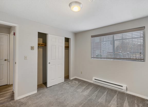 an empty bedroom with a window and a door to a closet