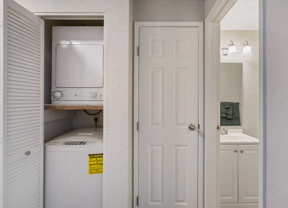 Stacked washer and dryer in shutter door closet to the left of a linen closet with bathroom on the right.at Capitol Crossing, Olympia, WA