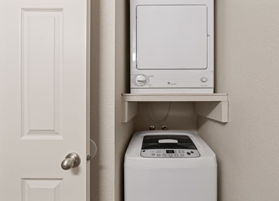a small laundry room with a washer and dryer and a white door