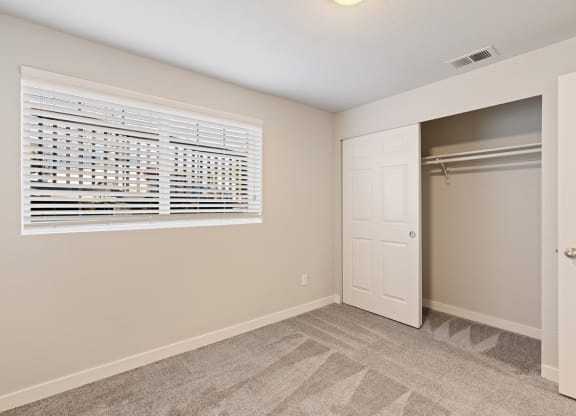 Carpeted bedroom, window with white blinds, and large sliding door closet with closet rod.at Capitol Crossing, Washington, 98501