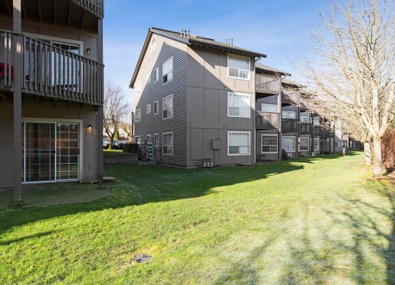 Exterior of Capitol Crossing Apartments with balconies and patios lined with green grass and trees.at Capitol Crossing, Washington