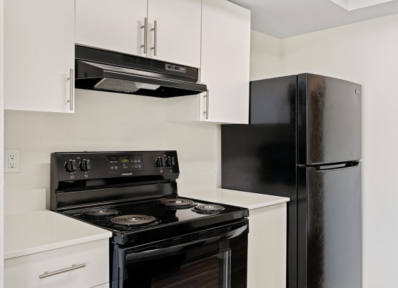 A close-up view of the kitchen with new white cabinets, an oven and stovetop, and a full-size fridge. at Pointe East, Washington, 98424