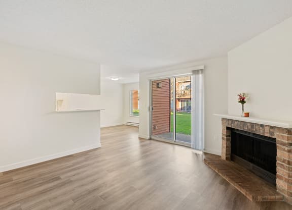 A living room with a white mantle above a brick fireplace and sliding glass doors to the left. at Pointe East, Fife, 98424