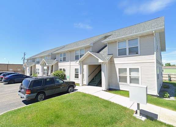 A two-story residential building with a car parked in front.