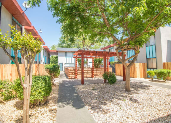 Outdoor courtyard with paved path and landscaping leading to pavilion and dog park.at Woodland Village , Woodland California