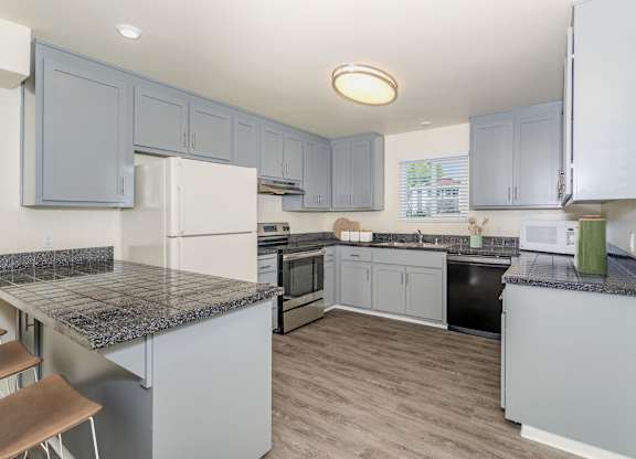 A kitchen with a granite counter top and grey cabinets at Gateway Student Apartments in Chico, CA.