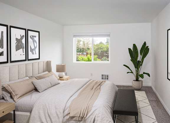 A large bedroom with a potted plant and a large window at our Renton Apartments
