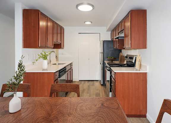 A kitchen with brown wooden cabinets and a white door at Heritage Grove Apartments in Renton, WA