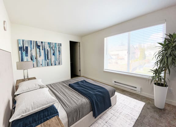 a bedroom with a large window, queen-size bed, and a door on the back wall.at The Trail, Snohomish