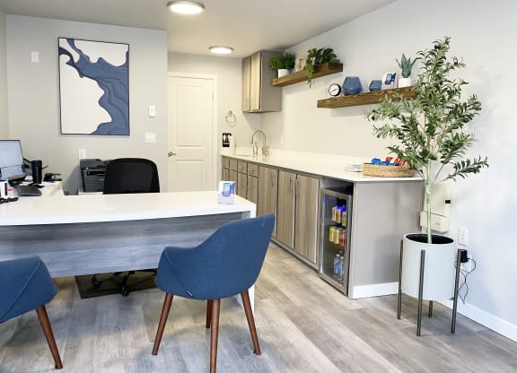 The Trail Apartments lobby office with a l-shaped desk, 2 blue chairs, and a mini fridge with drinks and snacks.at The Trail, Snohomish, WA