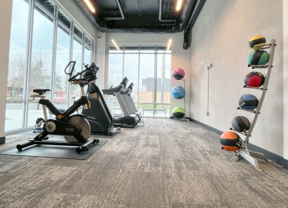 a gym with treadmills and weights at the district at highland village apartments at The Duo, University Place, WA 98466