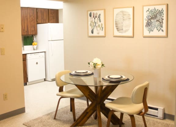 Dining Area that leads into kitchen. Staged with dining table, 2 chairs, wall art and a rug.at The Lakes Apartments, Washington