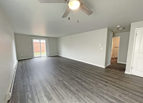Open layout living room with ceiling fan and sliding glass doors on the back wall to private fenced-in patio.at Quilceda Gardens, Washington, 98270