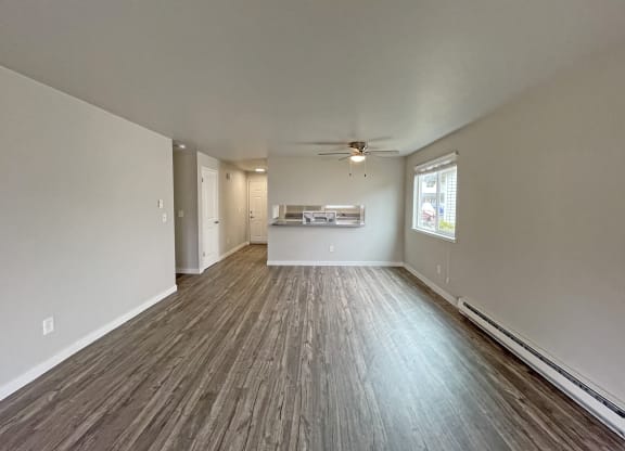 Spacious living room with dining area looking into kitchen with wood-like flooring and oversized window on the right.at Quilceda Gardens, Marysville, WA