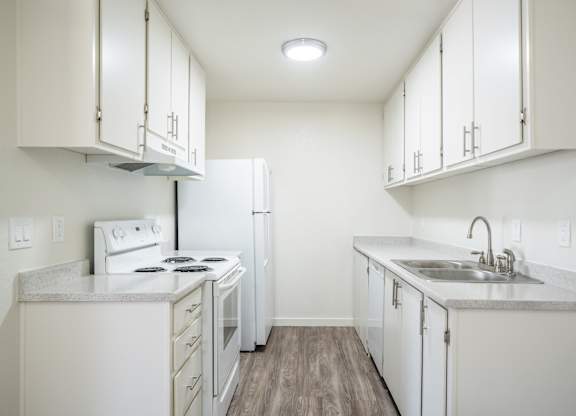an empty kitchen with white appliances and white cabinets at Kirkwood Meadows Apartments in Pocatello, ID