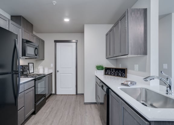 Length perspective of kitchen. with countertops on each side. Pantry door at the end of the kitchen. at Altitude, East Wenatchee, 98802
