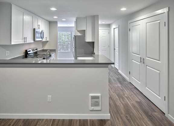 an empty kitchen with white cabinets and a large counter top  at Edmonds Gateway, Edmonds, WA, 98026