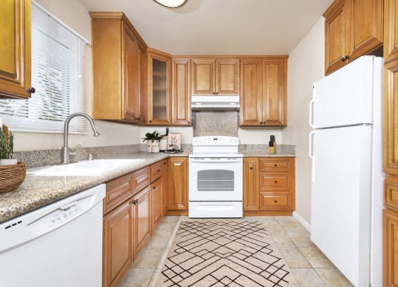 Large U-shaped kitchen with granite countertops, dishwasher, sink, stove, oven and fridge at Pacific Sands, San Diego, California