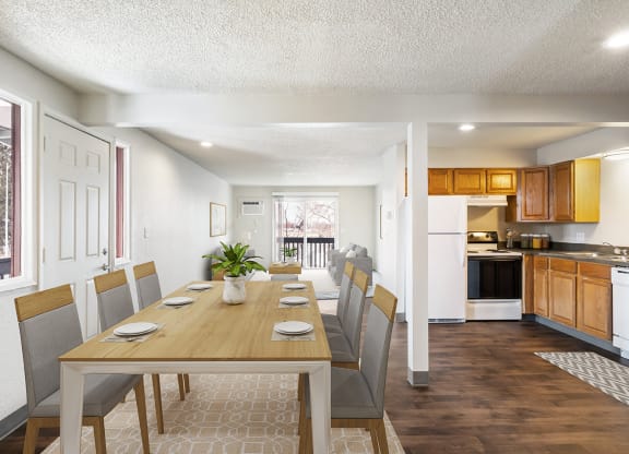 A dining area with a wooden table and chairs and a kitchen and living room in the background at Wildflower, Kennewick, WA 99336