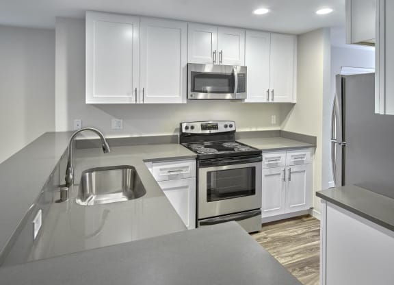 an empty kitchen with white cabinets and stainless steel appliances  at Edmonds Gateway, Washington
