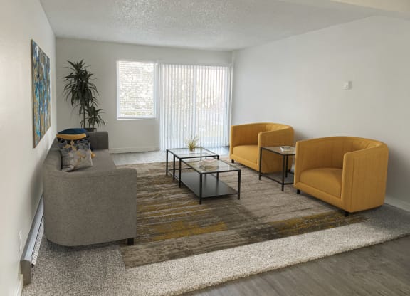 Carpeted living room, large window, sliding glass doors to balcony on back wall, staged with 2 orange chairs, couch, coffee table.at Laurel Park, Twin Falls, ID